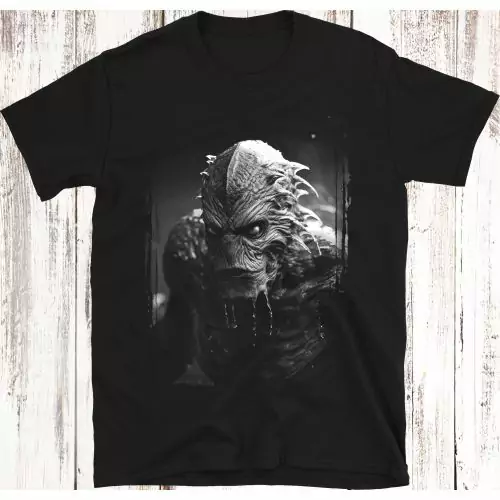 Umarme die Tiefen der Angst mit unserem exklusiven T-Shirt, das das furchterregende Gillman aus "Creature From The Black Lagoon" zeigt; ein Symbol für aquatische Horror, filmische Bedrohung und Komfort mit einem Hauch von Schauder.